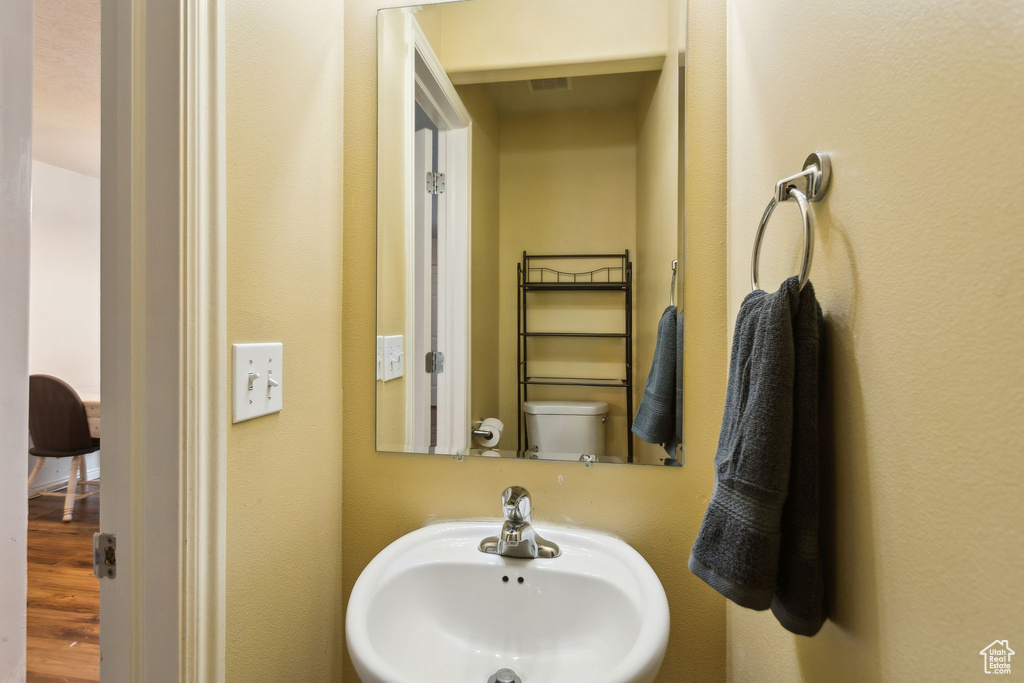 Bathroom with a sink, wood finished floors, and toilet