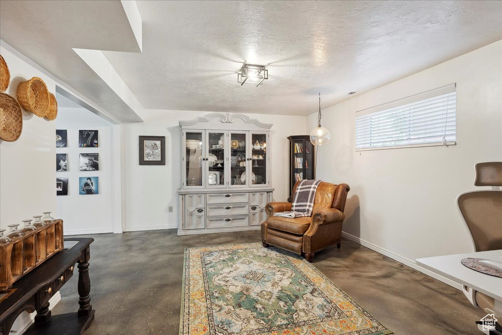 Sitting room featuring finished concrete floors, a textured ceiling, and baseboards