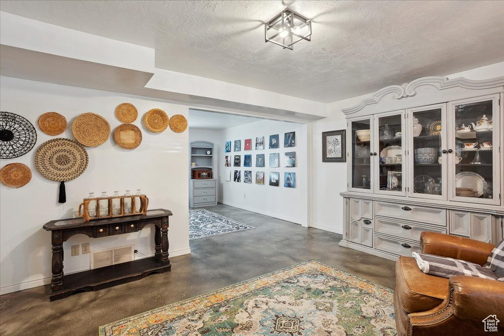 Living area with concrete floors, baseboards, arched walkways, and a textured ceiling
