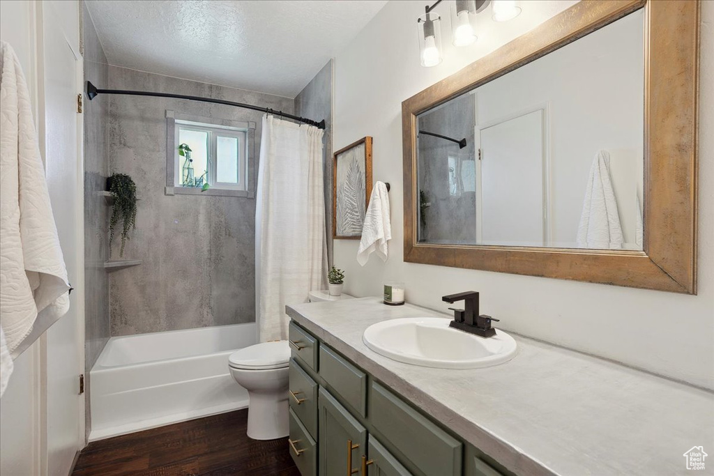 Full bath with vanity, shower / tub combo, wood finished floors, and toilet