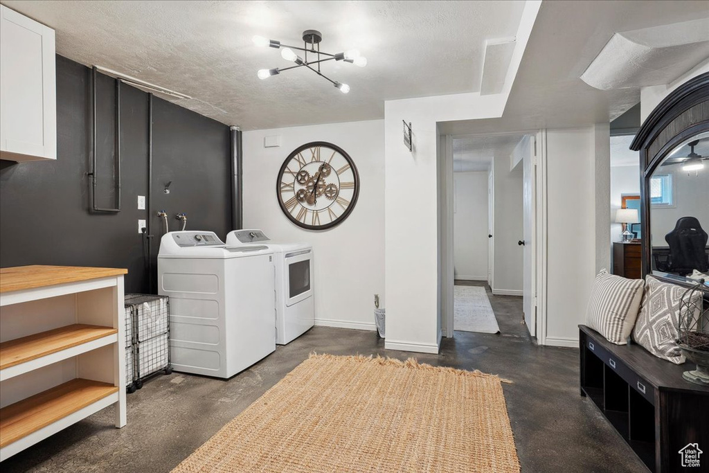 Laundry room with washing machine and dryer, a chandelier, and baseboards
