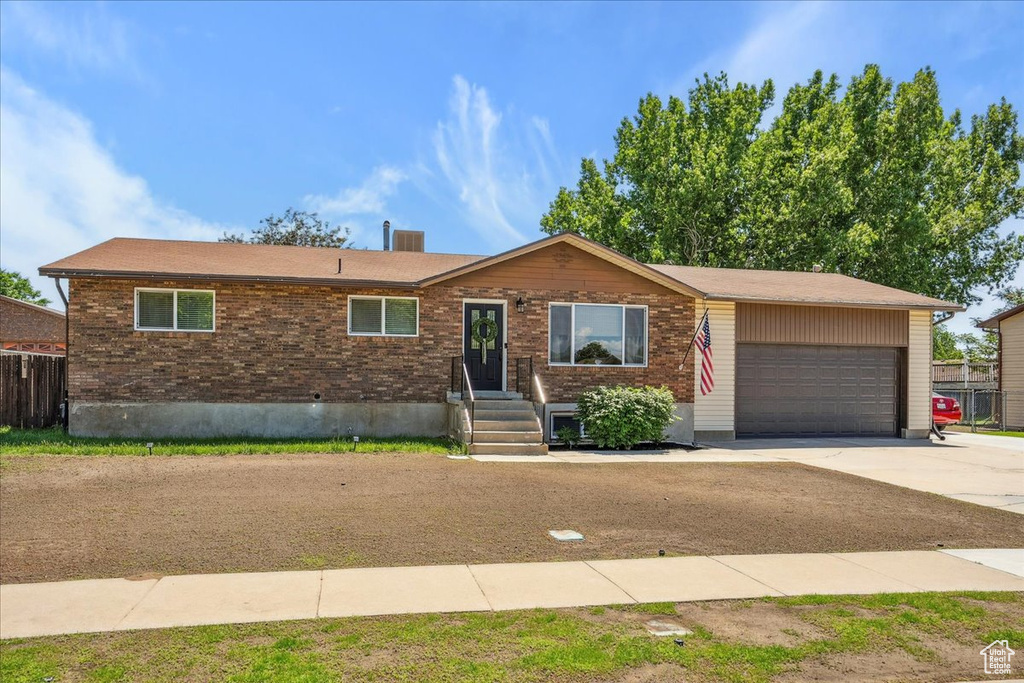 Ranch-style home with concrete driveway, an attached garage, and brick siding
