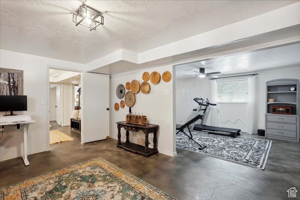 Workout area featuring baseboards, a textured ceiling, and a ceiling fan