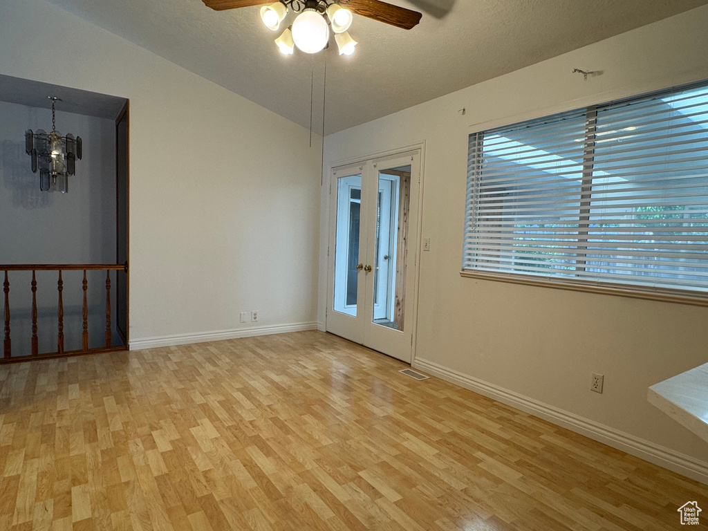 Spare room featuring light wood finished floors, ceiling fan, baseboards, and a chandelier