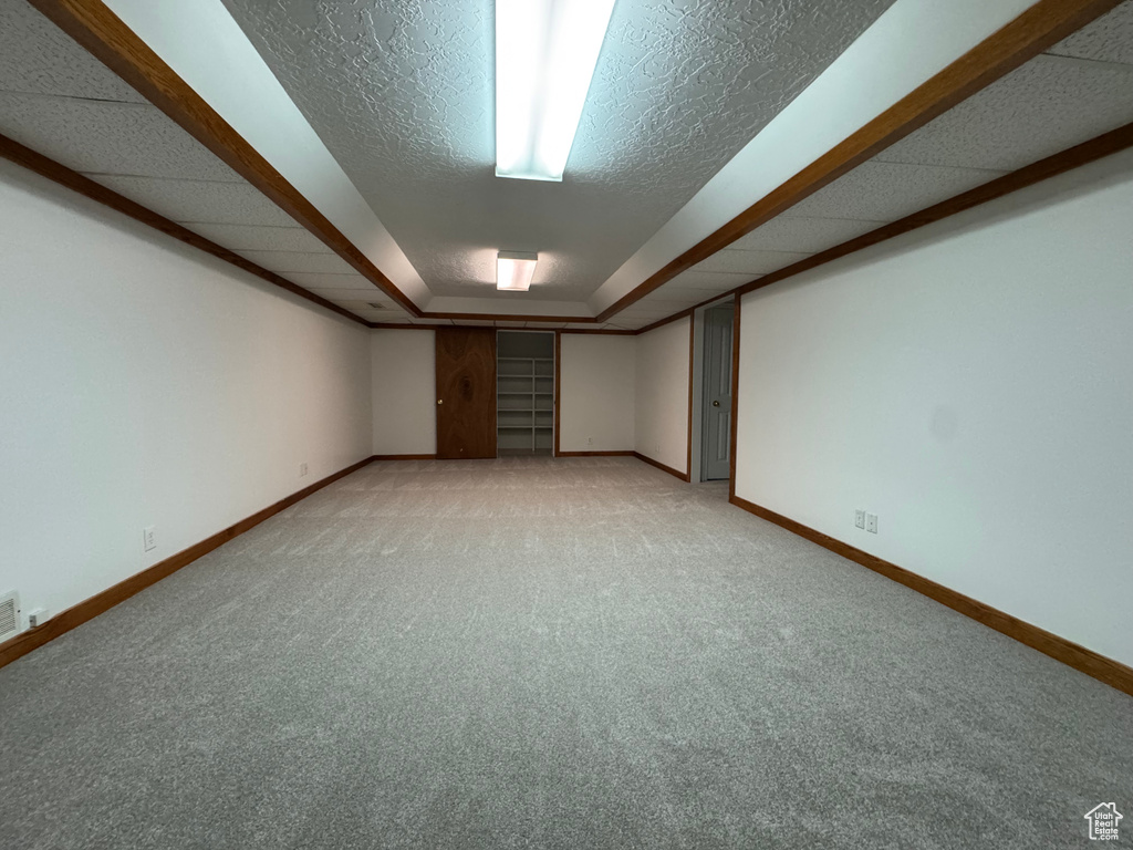 Finished below grade area with baseboards, light colored carpet, and a textured ceiling