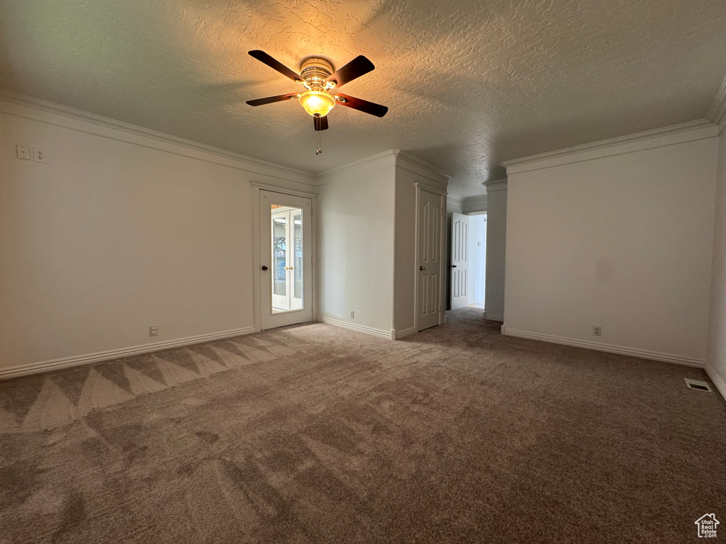 Carpeted empty room with a ceiling fan, a textured ceiling, ornamental molding, and baseboards