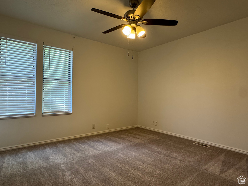Empty room featuring carpet floors, ceiling fan, and baseboards