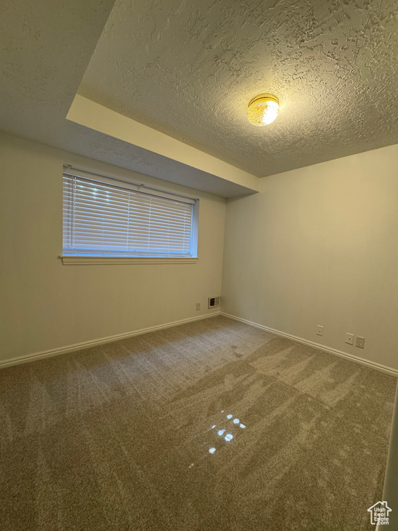 Carpeted empty room with a textured ceiling and baseboards