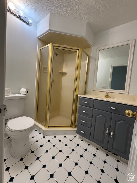 Bathroom with vanity, a shower stall, tile patterned floors, toilet, and a textured ceiling