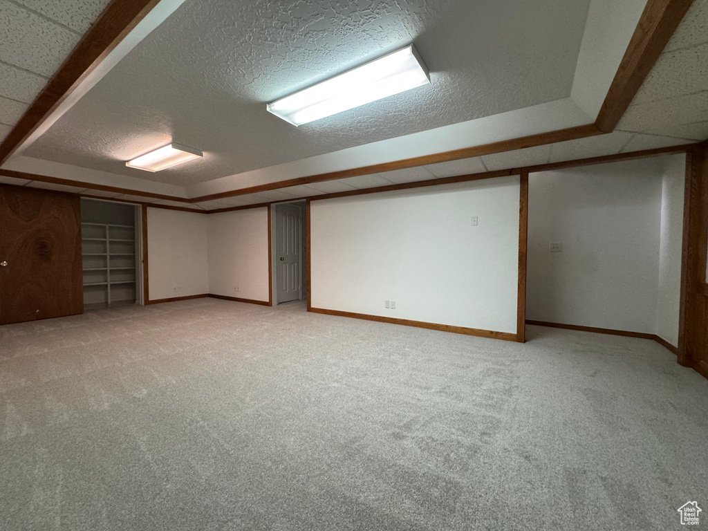 Finished basement with light colored carpet, baseboards, and a textured ceiling