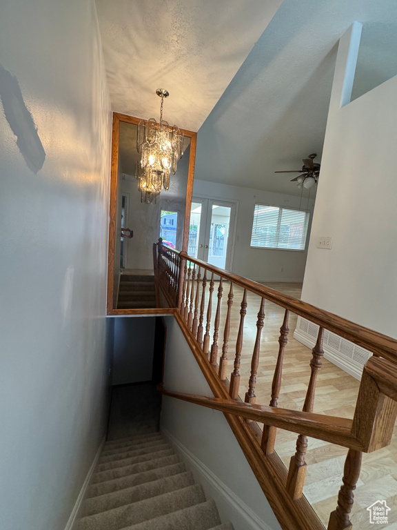 Stairway with a chandelier, ceiling fan, and baseboards