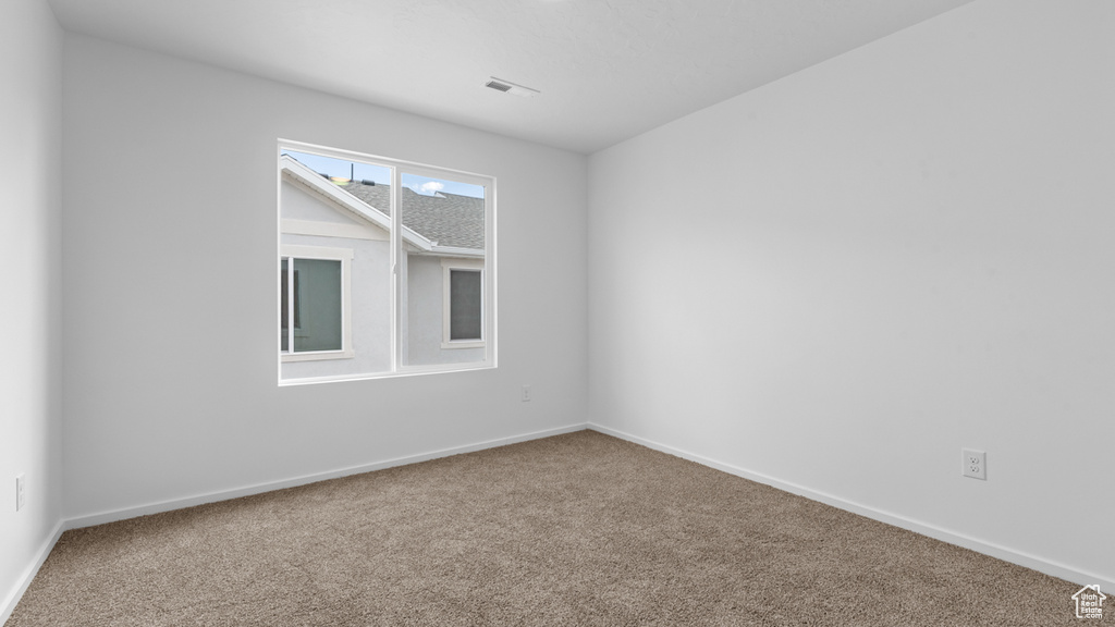 Carpeted empty room featuring baseboards