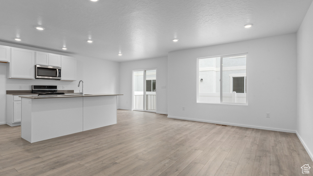 Kitchen featuring stainless steel microwave, stove, recessed lighting, light wood-style floors, and white cabinets