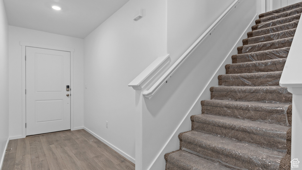 Stairs featuring wood finished floors, baseboards, and recessed lighting