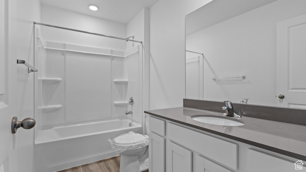 Full bath with vanity, wood finished floors, tub / shower combination, toilet, and recessed lighting