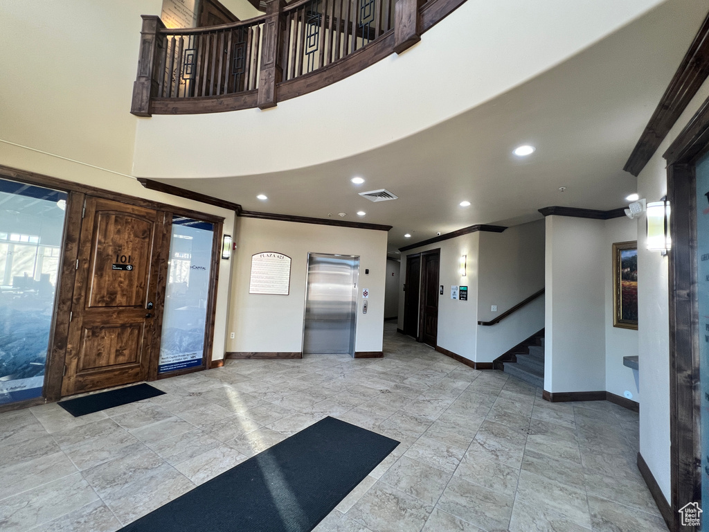 Building lobby featuring ornamental molding, stairway, and recessed lighting
