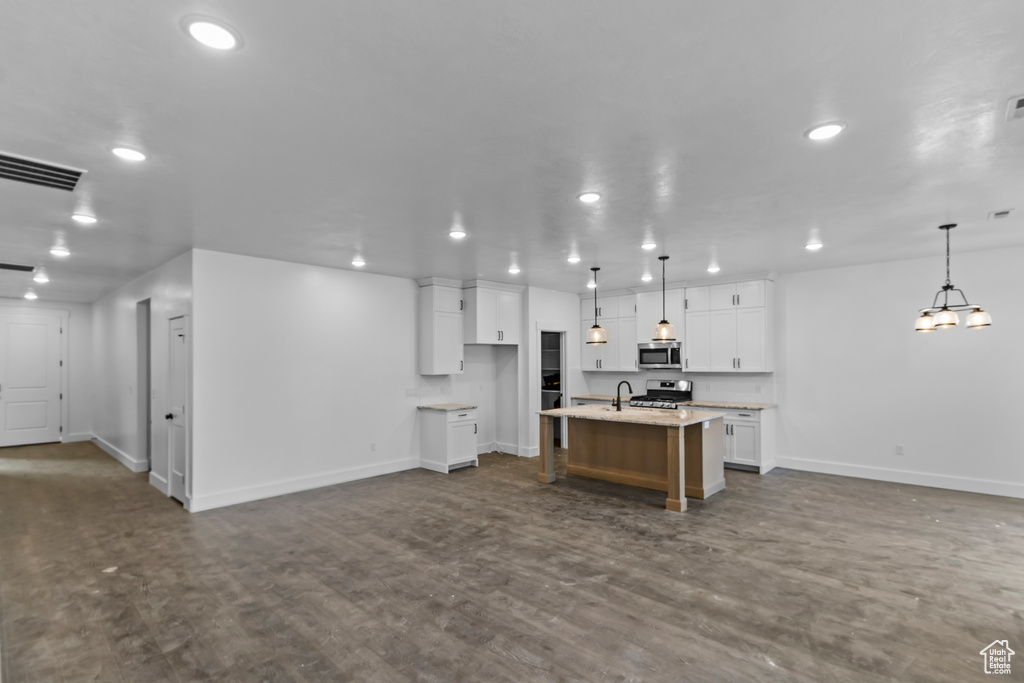 Kitchen featuring stainless steel appliances, open floor plan, baseboards, a center island with sink, and recessed lighting