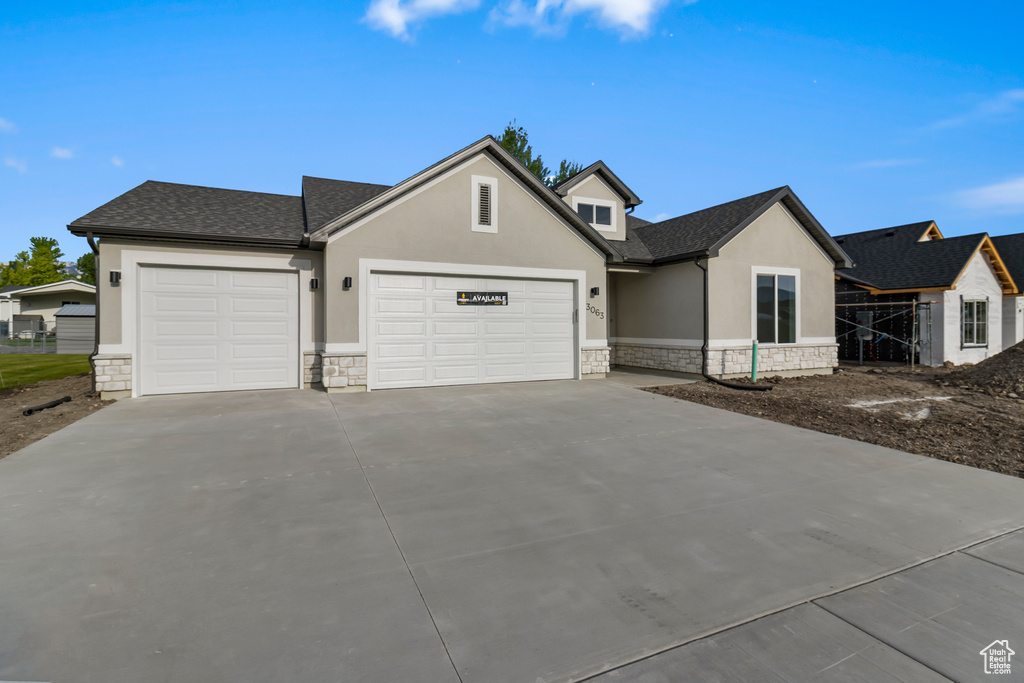 View of front of home with stone siding, stucco siding, an attached garage, and concrete driveway
