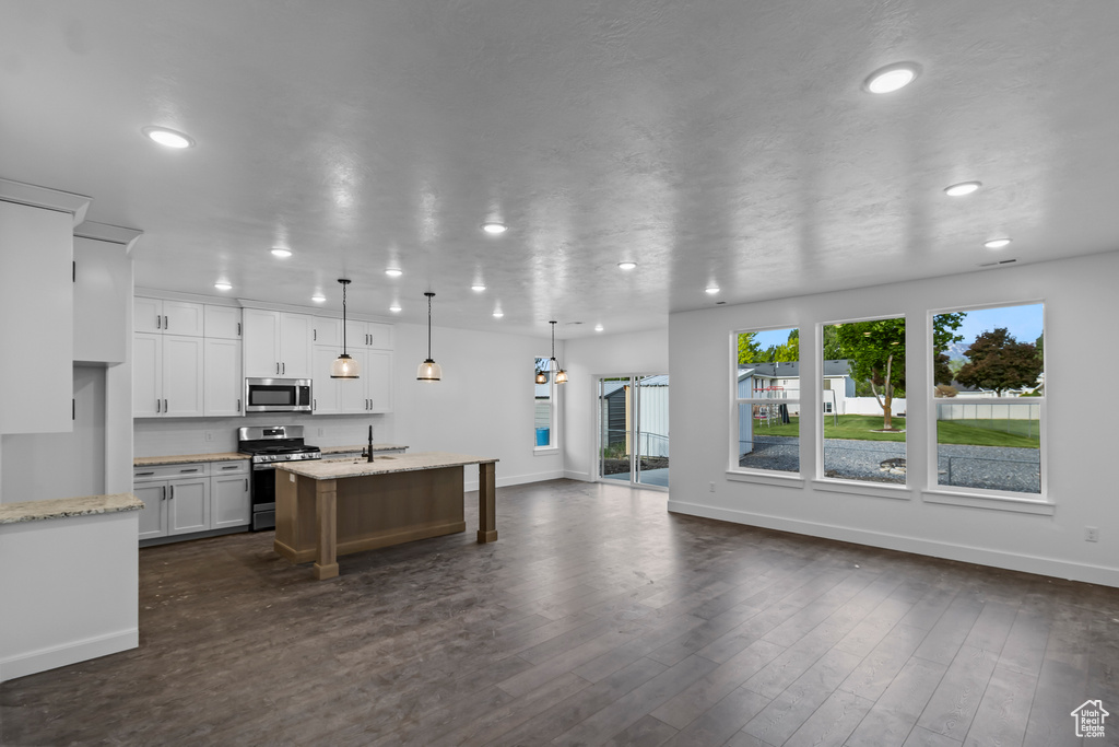Kitchen featuring stainless steel appliances, a sink, baseboards, recessed lighting, and a kitchen island with sink