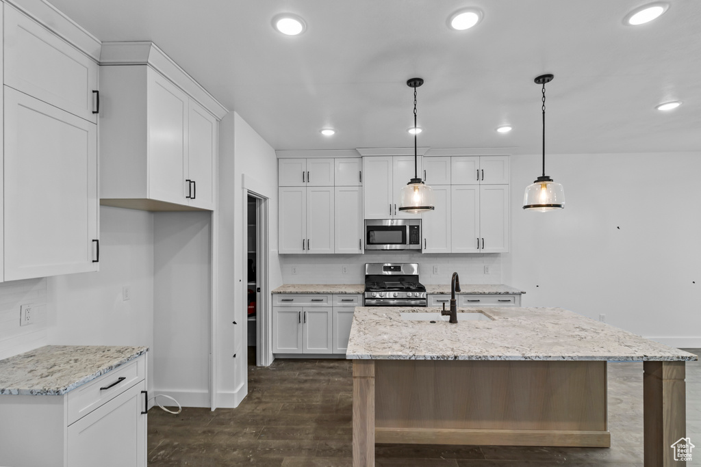 Kitchen with stainless steel appliances, a sink, baseboards, recessed lighting, and white cabinetry