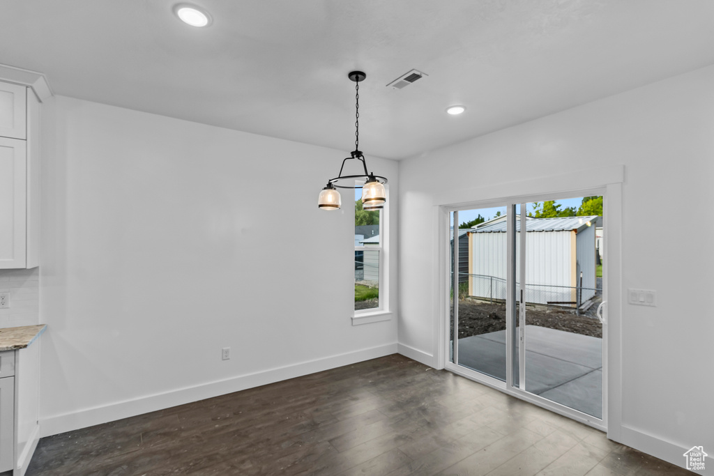 Unfurnished dining area with baseboards, recessed lighting, dark wood finished floors, and a chandelier
