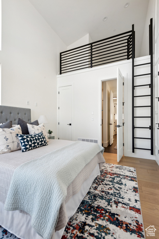 Bedroom featuring high vaulted ceiling and light wood-type flooring