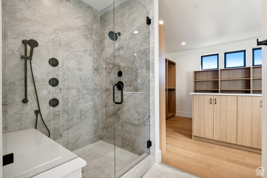 Full bath featuring a stall shower, wood finished floors, baseboards, and recessed lighting