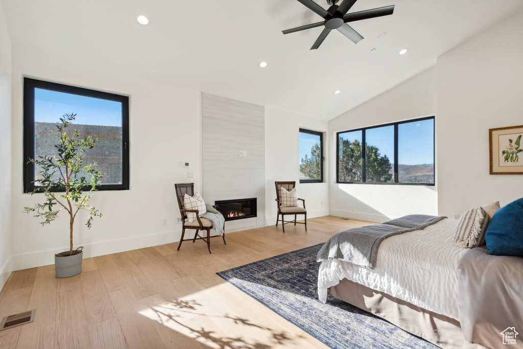 Bedroom with recessed lighting, a large fireplace, light wood finished floors, baseboards, and high vaulted ceiling