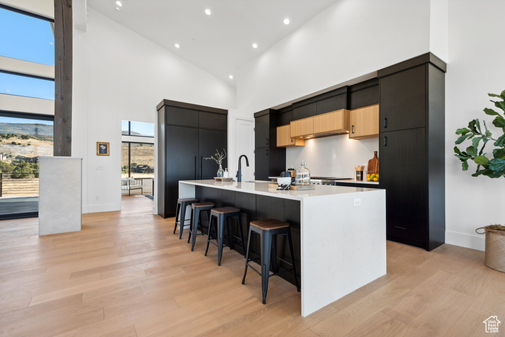 Kitchen with a high ceiling, modern cabinets, a kitchen bar, a large island, and recessed lighting