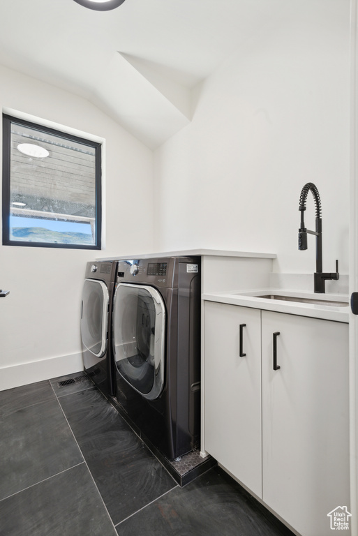 Laundry area featuring washing machine and dryer, a sink, and baseboards