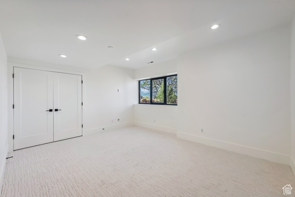 Unfurnished bedroom with recessed lighting, baseboards, light carpet, and a closet