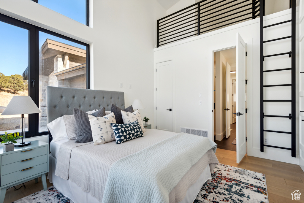 Bedroom featuring a towering ceiling and light wood-type flooring