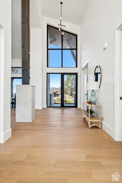 Foyer featuring a towering ceiling, light wood-style flooring, and baseboards