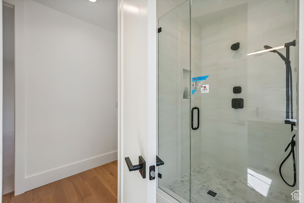 Bathroom with a shower stall, wood finished floors, and baseboards