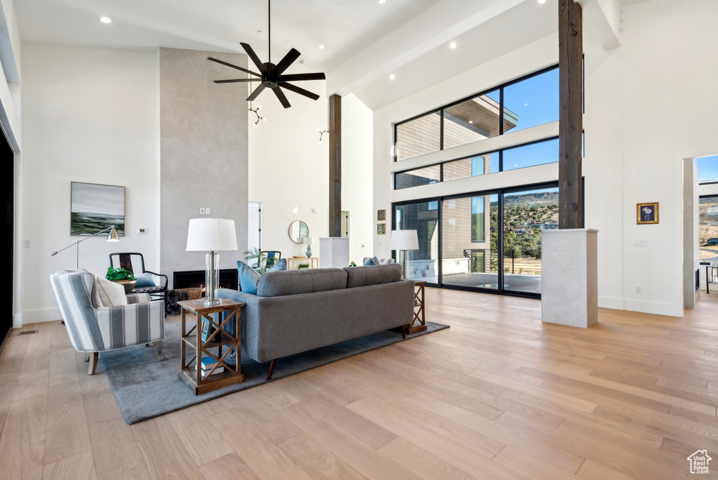 Living room with a towering ceiling, a ceiling fan, wood finished floors, baseboards, and recessed lighting
