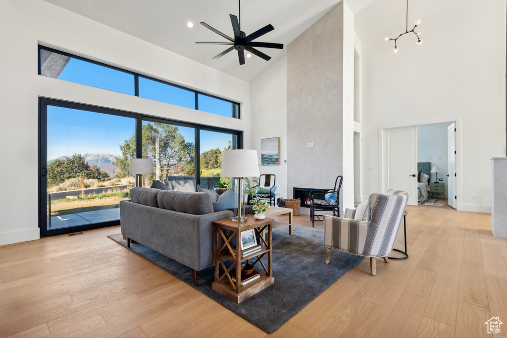 Living area featuring a towering ceiling, light wood-style flooring, a ceiling fan, baseboards, and recessed lighting