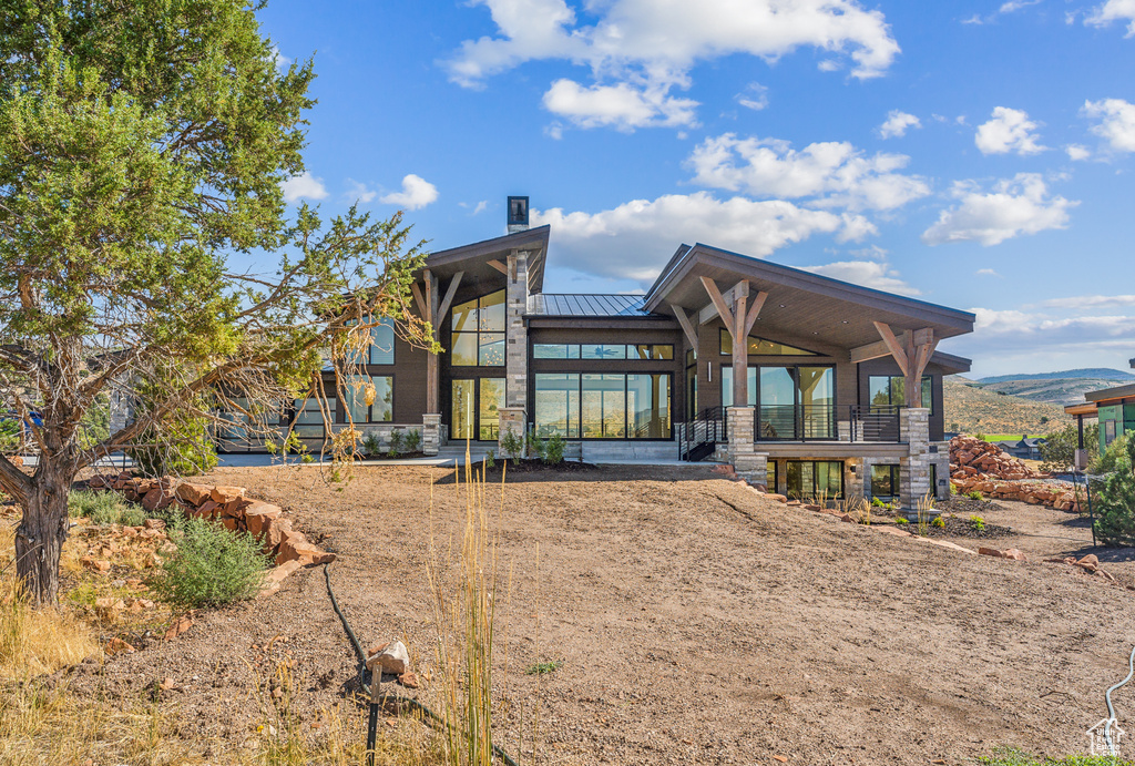 Back of house featuring a standing seam roof, metal roof, stone siding, and a mountain view