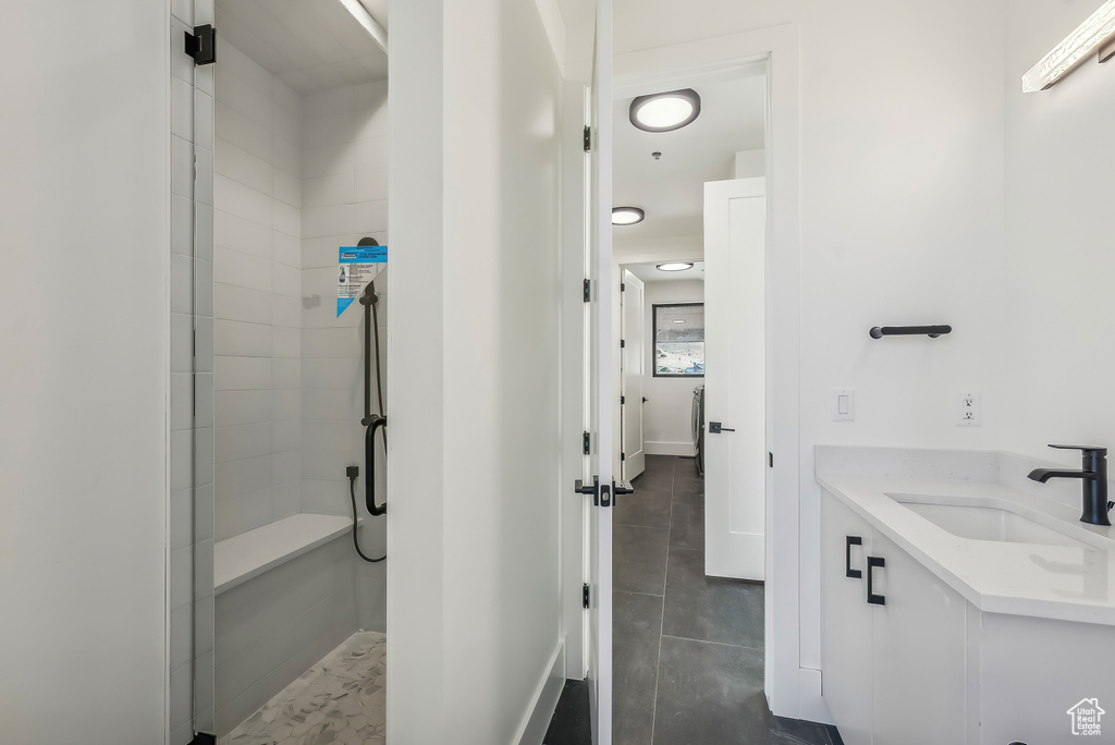 Full bathroom featuring a tile shower, vanity, and baseboards