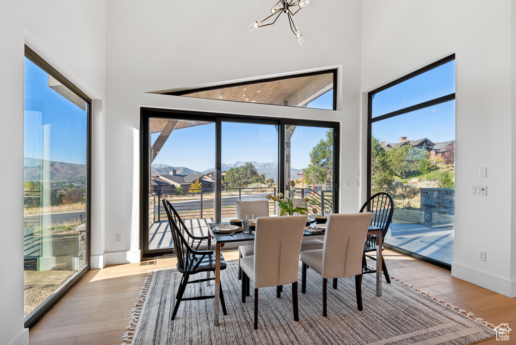 Dining area featuring a high ceiling, light wood-style flooring, a chandelier, and baseboards