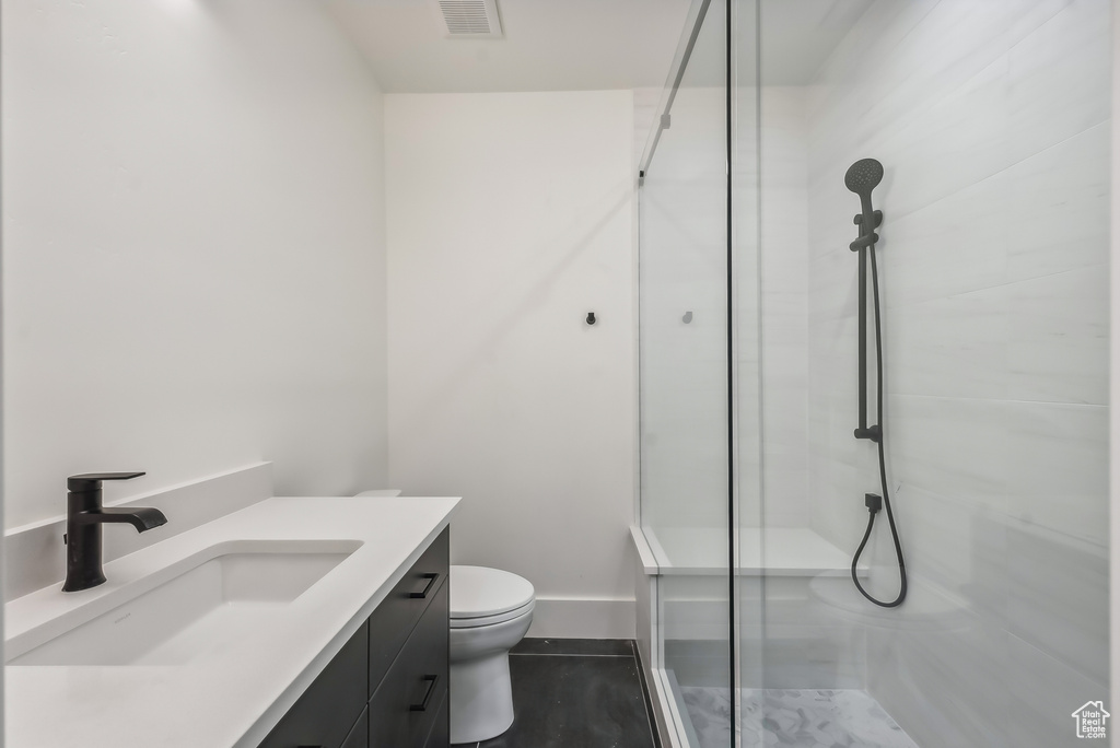 Bathroom with a stall shower, vanity, toilet, and baseboards