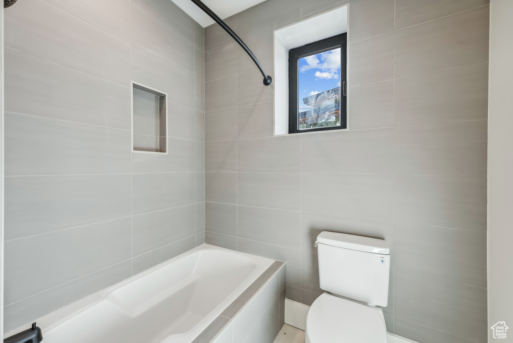 Full bathroom with toilet, tile walls, and  shower combination