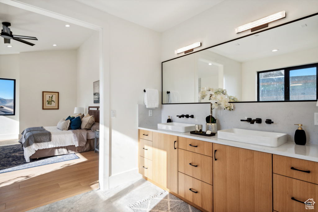 Full bath featuring connected bathroom, double vanity, wood finished floors, ceiling fan, and recessed lighting