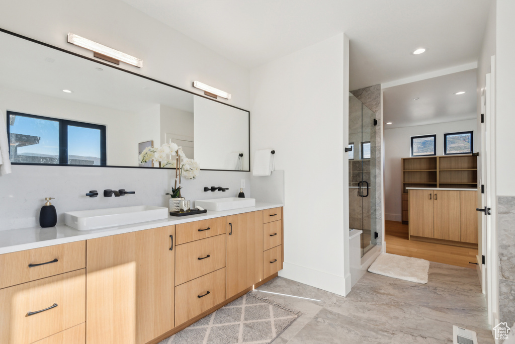 Bathroom featuring double vanity, a shower stall, and recessed lighting