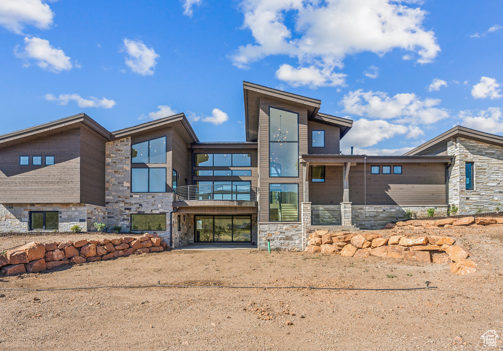 Rear view of property featuring stone siding and a balcony
