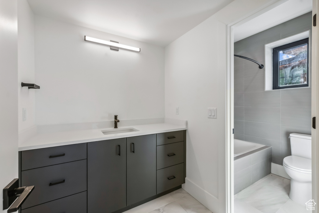 Full bathroom with vanity, toilet, tiled shower / bath, and baseboards
