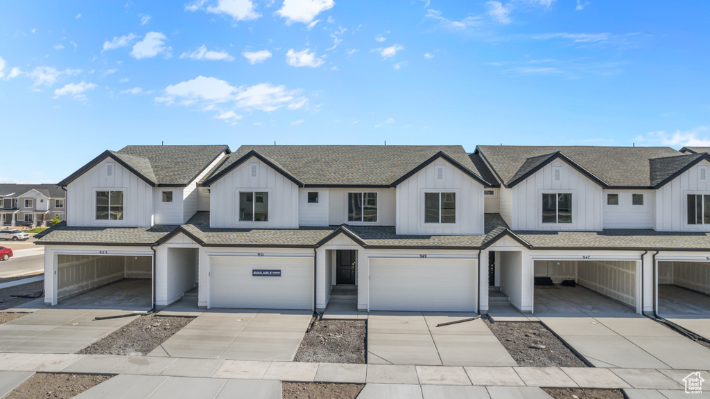 Townhome / multi-family property featuring board and batten siding, a shingled roof, an attached garage, and driveway