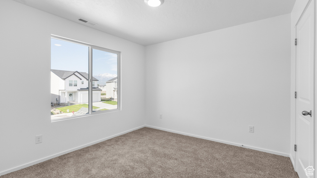 Carpeted spare room featuring baseboards