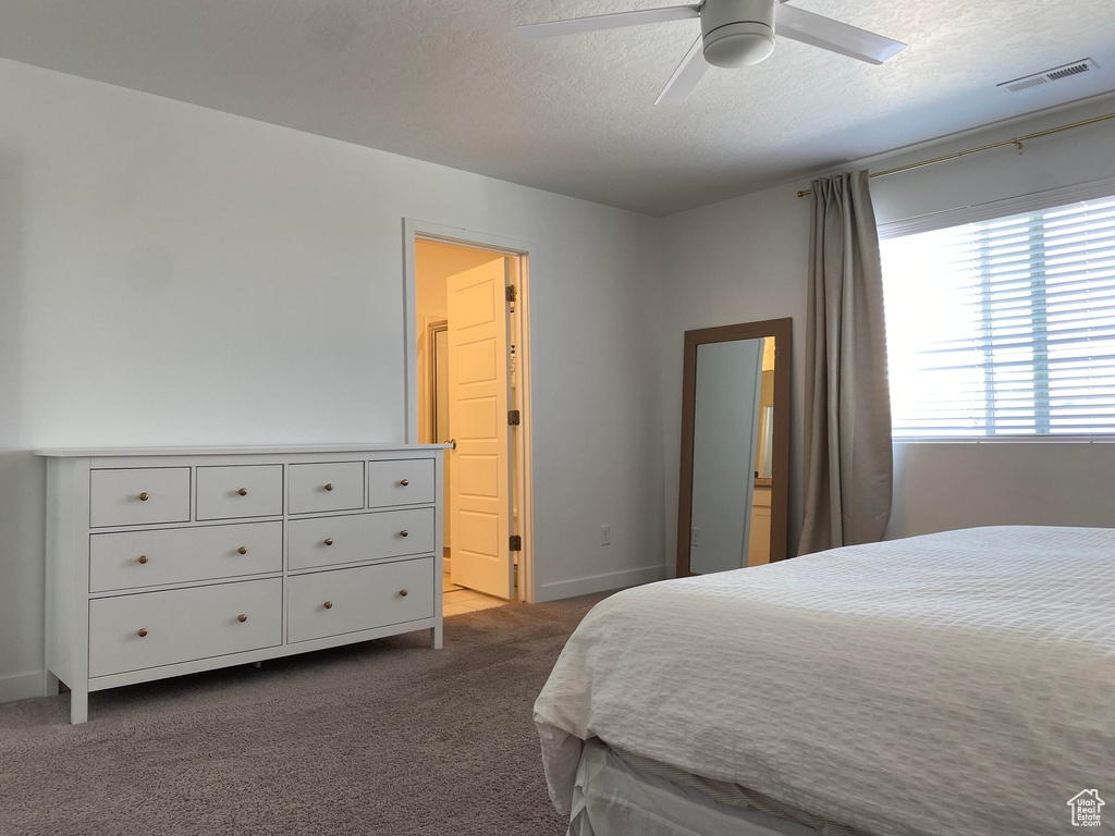 Bedroom featuring a textured ceiling, dark colored carpet, baseboards, and ceiling fan