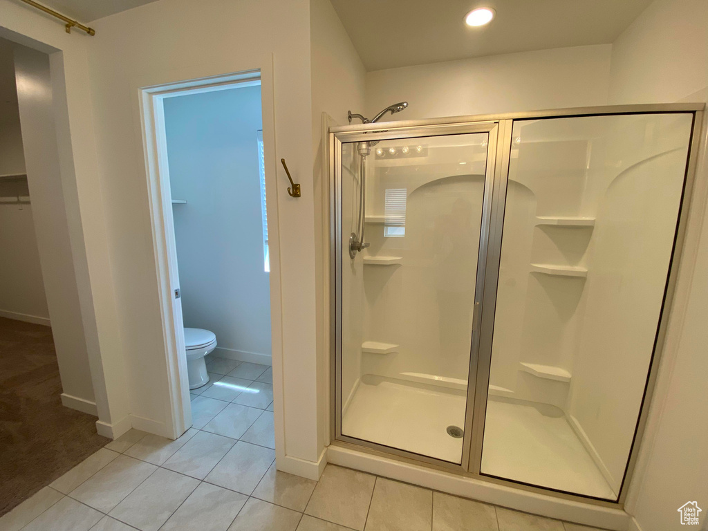 Bathroom featuring a shower stall, toilet, tile patterned floors, baseboards, and recessed lighting