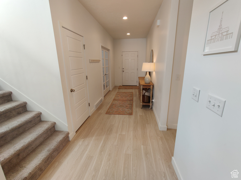Hallway featuring light wood finished floors, recessed lighting, baseboards, and stairs